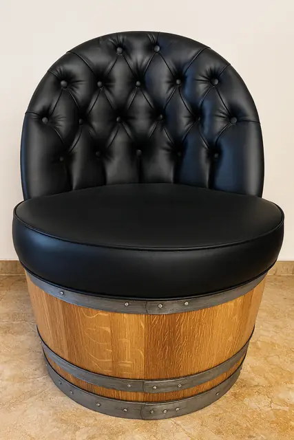 An armchair built into a halved barrel, upholstered in buttoned black leather.